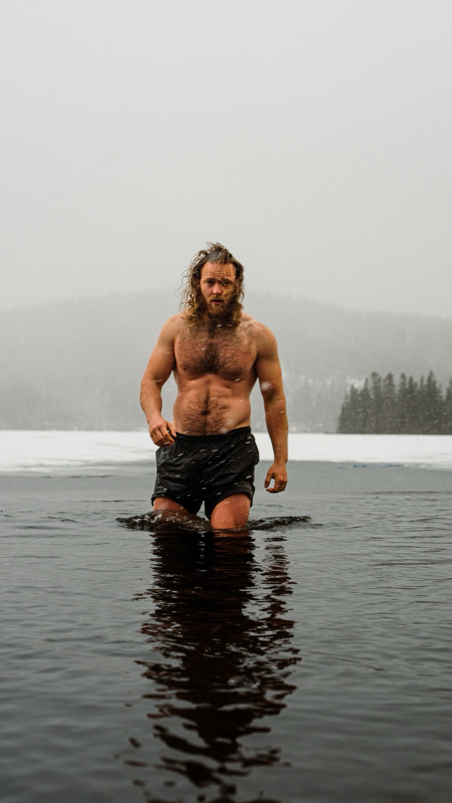 A cold-water swimmer wading out of a misty winter lake